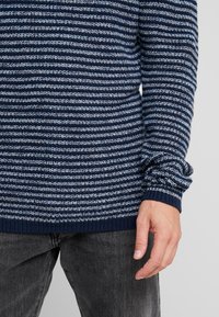 Maglione a righe blu navy e azzurro chiaro in maglia strutturata. Presenta un collo e polsini a costine, una vestibilità rilassata e maniche lunghe.