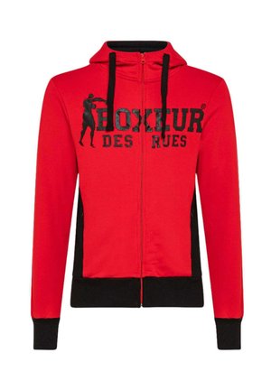 Roter Zip-Hoodie mit schwarzen Seitenpaneelen. Mit Kapuze, schwarzen Kordeln und einem auffälligen schwarzen Drucktext über der Brust. Weicher Stoff.