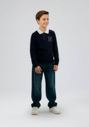 Marineblauwe polo met lange mouwen, witte kraag en een geborduurde letter "N" in blauw. Gecombineerd met losvallende blauwe jeans en witte sneakers.