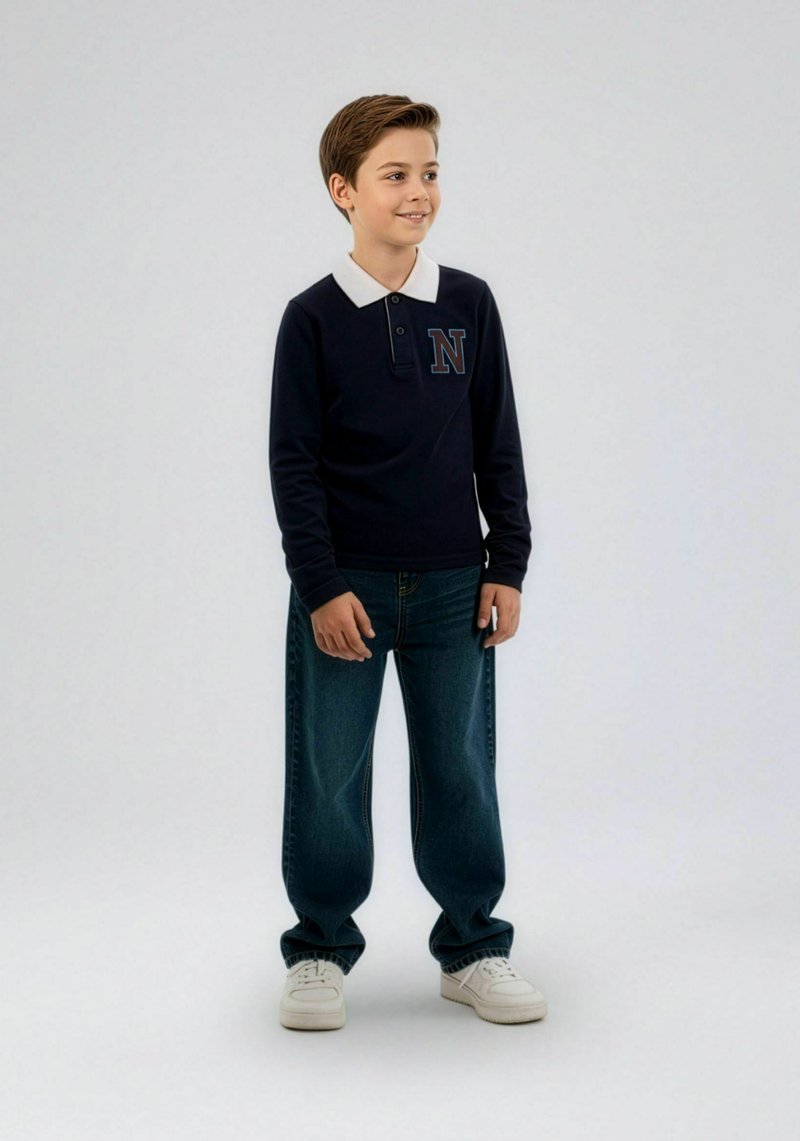 Tumši zils polo krekls ar garām piedurknēm, baltu apkakli un izšūtu zilā krāsā burtu "N". Combīnāts ar brīva piegriezuma zilām džinsu biksēm un baltām sporta kurpēm.