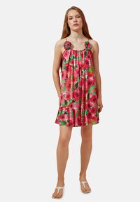 Vestido sin mangas de flores rosadas con detalles verdes, escote fruncido y dobladillo con volantes. Presenta adornos de rosas en los tirantes.