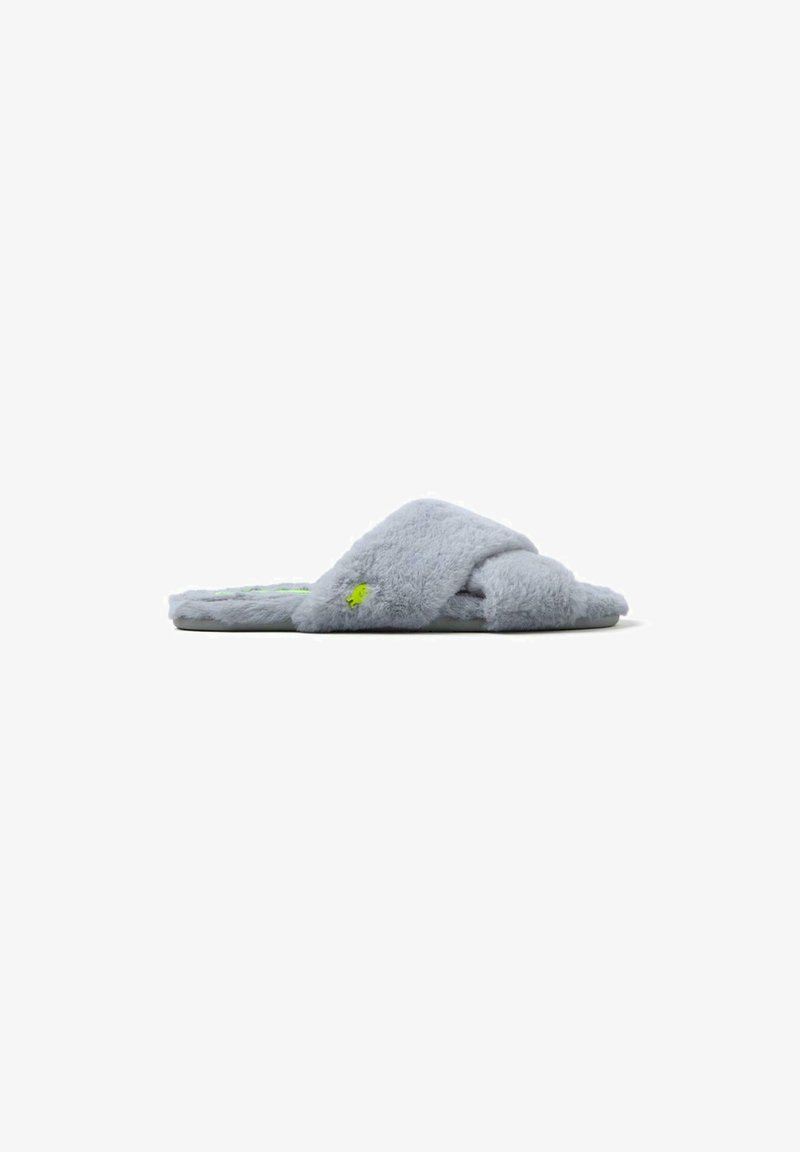 Chausson en peluche gris à design croisé, avec un logo accentué en vert et une texture douce. Semelle plate pour un usage intérieur.