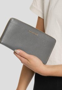 Billetera de cuero gris con textura de grano. Los herrajes en tono dorado llevan el nombre de la marca "LAZAROTTI". La billetera tiene un diseño con cierre de cremallera alrededor.