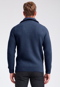 Maglione a costine blu navy con colletto a scialle, caratterizzato da maniche lunghe e un orlo inferiore aderente, mostrato da dietro.