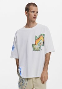 Balta per didelį dydį marškinėliai su spalvingais grafinių atspaudų dizainais ant priekio ir rankovių. Pagaminta iš minkštos medvilnės, su apvaliu iškirpimu ir trumpomis rankovėmis.