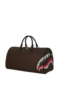 Bolsa de deporte marrón con ribetes negros, que presenta un gráfico de boca de tiburón en rojo y blanco, herrajes dorados y dos asas negras.