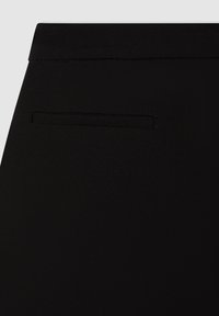 Pantaloni neri con una texture liscia, caratterizzati da una discreta tasca posteriore e una vita standard. Design minimalista senza ferramenta visibile.
