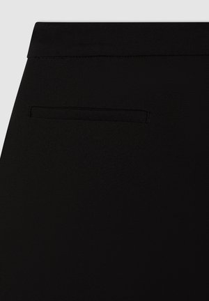 Pantaloni neri con una texture liscia, caratterizzati da una discreta tasca posteriore e una vita standard. Design minimalista senza ferramenta visibile.