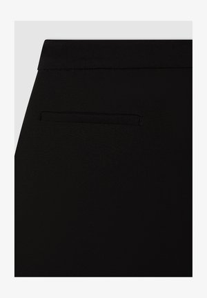 Pantaloni neri con una texture liscia, caratterizzati da una discreta tasca posteriore e una vita standard. Design minimalista senza ferramenta visibile.