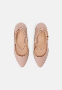 Ballerines nudes en cuir avec un bout pointu, dotées de deux brides et de quincaillerie dorée. Texture lisse et design minimaliste.