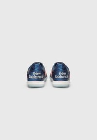 Plave atletske cipele s ružičastim akcentima, s teksturiranim sintetičkim gornjim dijelom, mekanim ovratnikom i logotipom "New Balance" na peti.
