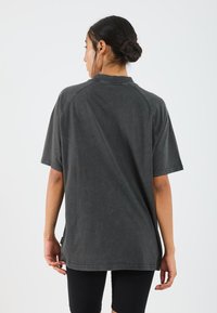 Donkergrijze oversized t-shirt met korte mouwen, zachte textuur, ribbelige halslijn en zijsplitten aan de zoom.