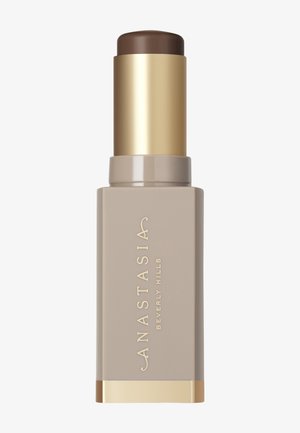 Stockfundament mit braunem Oberteil und goldenen Akzenten. Der Körper ist beige mit geprägtem Branding. Glatte Textur, zylindrische Form.