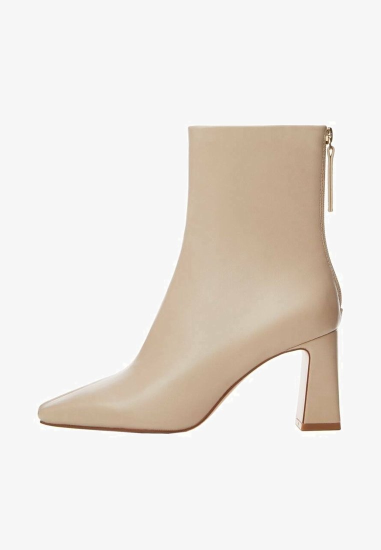 Bottine beige en cuir lisse, avec un bout pointu, un talon bloc et une fermeture zippée sur le côté.