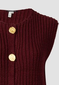 Bordeaux-farbene gestrickte ärmellose Bluse mit strukturiertem Design und zwei goldenen Knöpfen vorne. Das Etikett gibt die Größe 44 an.