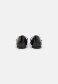 Loafers din piele patent neagră cu toc mic, textura netedă și detalii de cusătură pe spate. Design minimalist fără elemente de fixare vizibile.