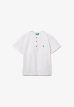 Camisa blanca de manga corta con cuello redondo, tres botones marrones en la tapeta y un bolsillo en el pecho con un botón a juego.