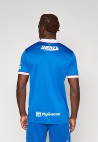 Königsblaues Sporttrikot mit weißem Kragen und roten Akzenten. Auf der Rückseite befindet sich das "SEKO"-Logo und das "MyGuava"-Logo nahe dem Saum.