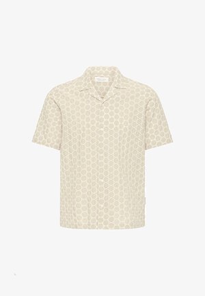 Chemise beige à manches courtes avec un devant boutonné et un motif de petits œillets circulaires sur tout le tissu.