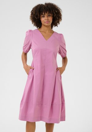Pink short-sleeve dress with a V-neckline, gathered puff sleeves, side pockets, and a flowing A-line shape. Smooth cotton fabric with a matte finish.