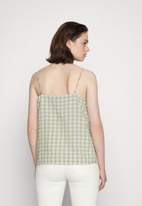 Camisola em xadrez verde e branco com alças ajustáveis e um corte descontraído, feita em tecido leve, exibida pela parte de trás.