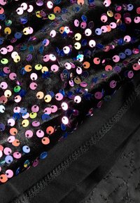 Tessuto nero con paillettes colorate e iridescenti che riflettono tonalità di rosa, blu e oro. Texture liscia con dettagli di cucitura a contrasto.