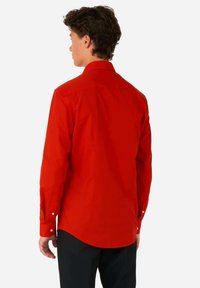 Rode langetermijn shirt van gladde stof, met een button-down kraag, rechte snit en button-up manchetten. Achteraanzicht toont de lengte van de staart.