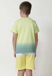 Tričko s krátkým rukávem ve světle zelené až tyrkysové barvě. V kombinaci se žlutými šortkami se vzorem tie-dye. Měkká látka, volný střih.