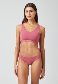Hellrosa Sport-BH und passende Bikini-Unterwäsche, gefertigt aus weicher Baumwolle. Beide haben ein schlichtes Design und elastische Bänder mit Logodetail.