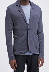 Grå stickad blazer med en avslappnad design, med en notched krage, enstaka knappstängning, två framfickor och en strukturerad tyg.