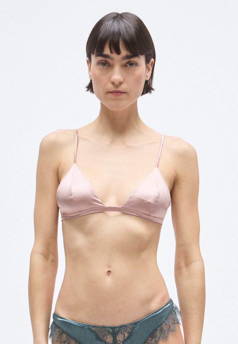 Ljusrosa satintriangel-bh med tunna band, med en slät textur och minimalistisk design, visas mot en neutral bakgrund.