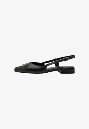 Chaussure slingback en cuir noir avec un bout pointu, un talon plat et un ornement doré décoratif à l'avant. Dotée d'une lanière fine et ajustable.