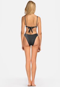 Czarny bikini o teksturowanej powierzchni z cienkimi ramiączkami i zawiązywaniem z tyłu. Wysoki stan dolnej części charakteryzuje się gładkim, bezszwowym designem.