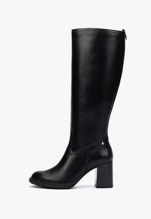 Botte haute en cuir noir avec un talon bloc et une couture décorative subtile sur le côté, vue de la face externe.