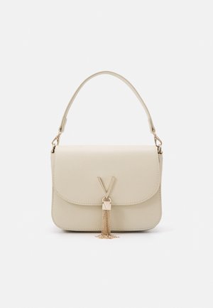 Handtasche aus cremefarbenem Leder mit einem oberen Griff, Klappenverschluss und goldfarbenem V-förmigem Verschluss mit hängenden Kettentasseln.