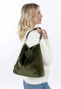 Grüne Plüsch-Handtasche mit weicher Textur, strukturiertem Design und einem einzelnen Ledertrageriemen. Verfügt über einen gerafften oberen Bereich mit Kordelzugverschluss.