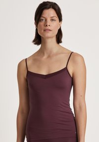 Bordeaux fitted tanktop met dunne bandjes en een V-hals. Gemaakt van een gladde, rekbare stof met een eenvoudig ontwerp en geen zichtbare patronen.