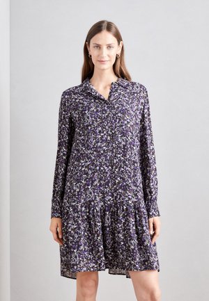 Kukallinen mekko tummassa violetissa, jossa on pitkät hihat, kauluksen näköinen kaulus ja kerrostettu helma, valmistettu kevyestä materiaalista.