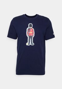 Námořnické bavlněné tričko s grafikou vojáka v červeném kabátu, který drží tenisovou raketu, s kulatým výstřihem, krátkými rukávy a hladkou texturou.