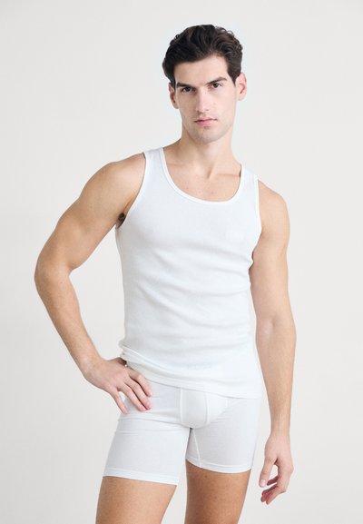 Débardeur blanc et boxer assorti, en tissu lisse ; coupe ajustée, texture douce, minimalisme de la marque sur la poitrine.