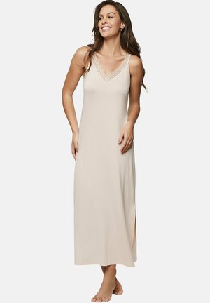 Nuisette longue sans manches en tissu beige doux, avec un décolleté en V orné de dentelle et des fentes sur les côtés pour plus de liberté de mouvement.