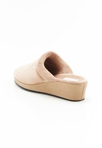 Sabots en plateforme beige avec un dessus doux et texturé et un bout arrondi. L'intérieur rembourré offre du confort, et le design présente un léger talon.
