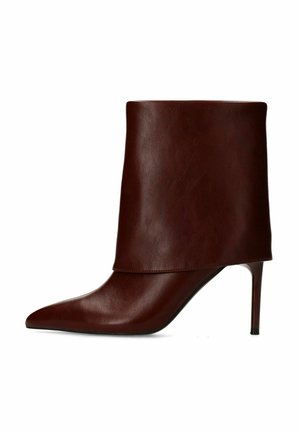 Donkerbruine leren laars tot halverwege de kuit met hoge hak, spits toelopende neus en smalle stilettohak, getoond op een witte achtergrond.