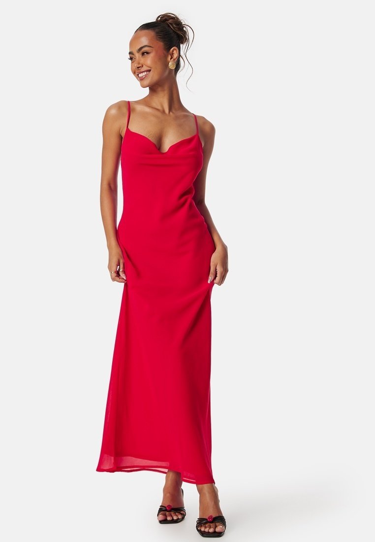 Robe maxi rouge avec des bretelles spaghetti, un décolleté drapé et une texture lisse. Présente une silhouette ajustée qui descend jusqu'au sol.