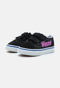 Mustat mokkanahkaiset Vans-kengät, joissa on tarranauhat, pinkki logo ja valkoinen pohja, jossa on sininen väriraita. Matalaprofiilinen muotoilu.