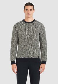 Maglione lavorato a maglia in bianco e nero con motivo a trama. Presenta uno scollo rotondo e polsini e orlo a coste. Design classico, maniche lunghe.