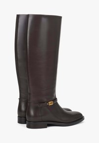 Brązowe skórzane kozaki za kolano o smukłym fasonie, z małą złotą klamrą i płaskim obcasem. Gładka faktura z połyskującym wykończeniem.