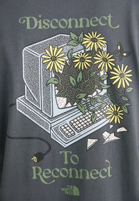 Grafika na koszulce przedstawiająca retro komputer otoczony żółtymi kwiatami i zielonymi liśćmi, z napisem "Odłącz się, aby połączyć się na nowo."