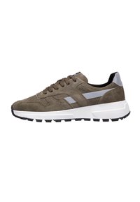 Zapatillas de ante marrón con suelas de goma blanca, detalles en gris y cordones marrones. Presenta un diseño perforado y una suela exterior resistente y texturizada.