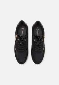 Baskets noires avec un dessus en tissu texturé, des accents en vernis brillant, des éléments en or et des lacets noirs, dotées d'une fermeture éclair sur le côté pour un enfilage facile.